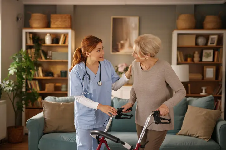 Nurse assisting elderly woman with walker.